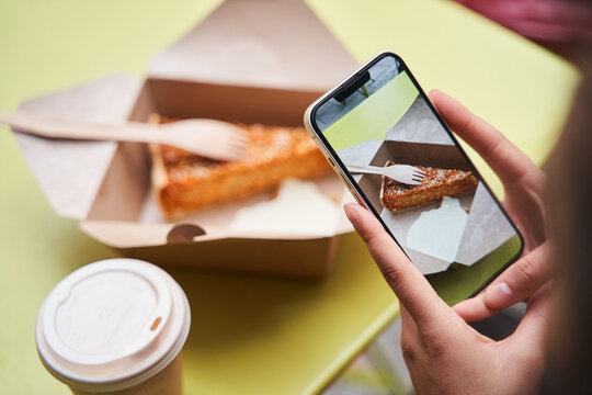 Cropped view of the woman hands holding her smartphone and shooting food