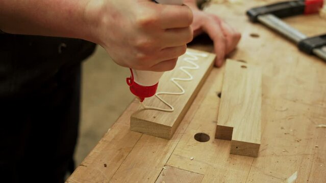 carpenter applying white glue on a wooden piece to stick it, making wooden crafts. High quality 4k footage