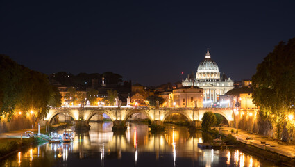 Fototapeta na wymiar Sant' Angelo Bridge and St. Peter's cathedral at night in Vatican City, Rome. Italy