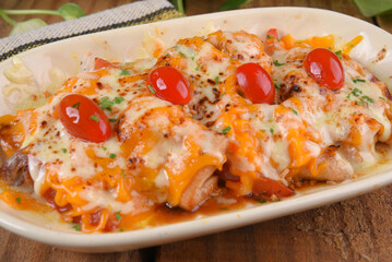 fried chicken with mozzarella cheddar cheese and cherry tomatoes and caramelized onion delicious food on wooden table