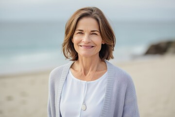 Portrait of smiling mature woman standing on beach with ocean in background