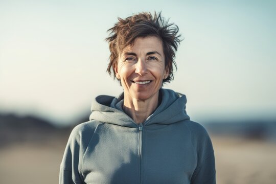 Medium shot portrait photography of a pleased woman in her 40s wearing a comfortable tracksuit against a summer landscape or beach background. Generative AI