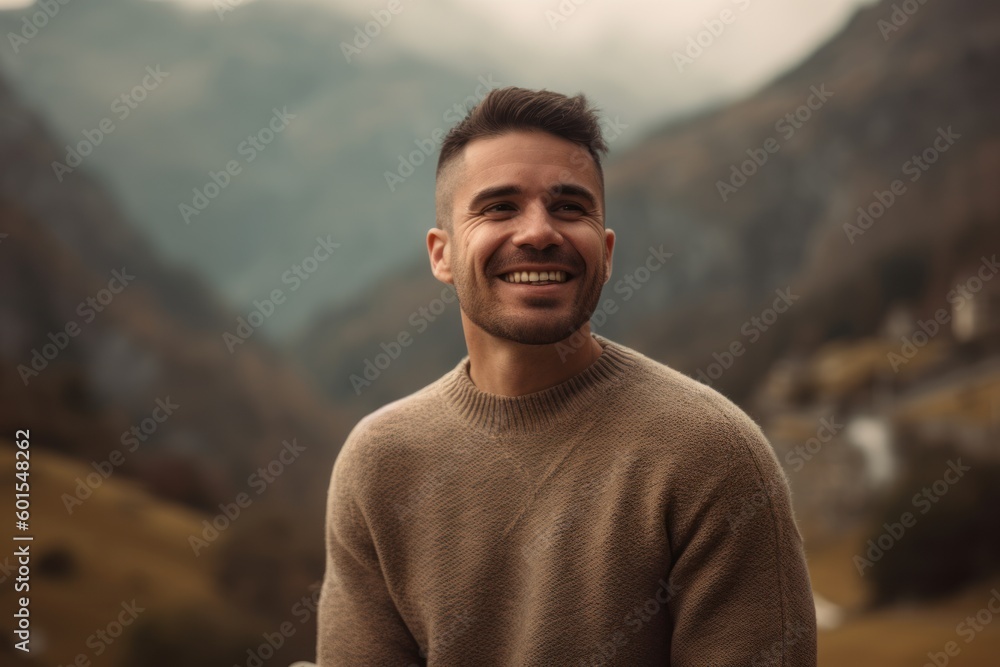 Wall mural Portrait of a handsome young man smiling and looking at camera in the mountains