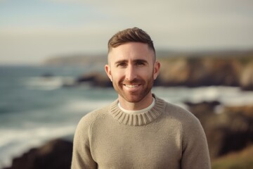 Portrait of handsome man smiling at camera while standing on the beach