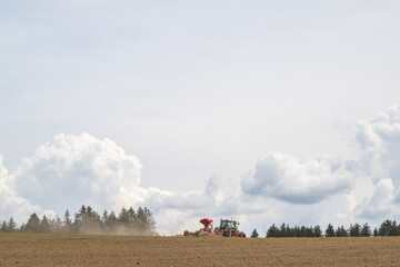 Fototapeta premium Sämaschine bei der Aussaat, vor Quellwolken