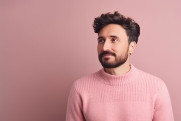 Fototapeta na wymiar Portrait of a handsome young man in a pink sweater on a pink background