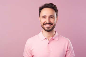 Portrait of a handsome young man smiling at the camera on a pink background