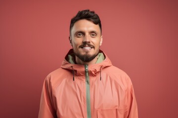 Obraz premium smiling young man in winter jacket looking at camera isolated on red