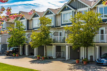 Nice neighborhood on a sunny day. Row of garage doors at parking area for townhouses.Garage door...