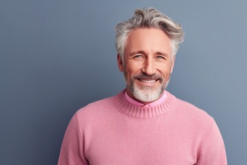 Obraz premium Portrait of a handsome mature man smiling and looking at camera while standing against grey background