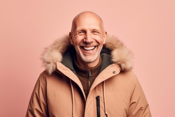 Portrait of happy senior man in winter jacket, isolated on pink background