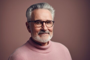 Fototapeta premium Portrait of a senior man with gray hair wearing glasses and a pink sweater.