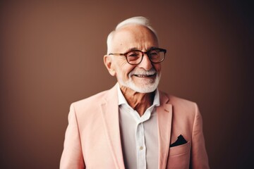 smiling senior man in eyeglasses looking at camera isolated on brown