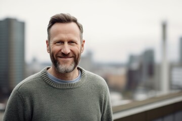 Obraz premium Portrait of a handsome middle-aged man in a gray sweater on the background of the city