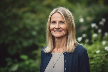 Portrait of smiling mature woman standing in the garden. Looking at camera.