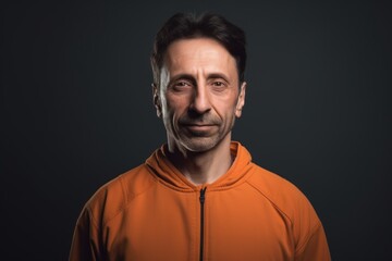 Portrait of a man in an orange hoodie on a dark background