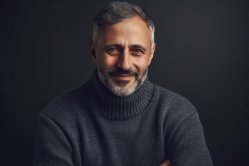 Fototapeta premium Portrait of a handsome middle-aged man in a gray sweater on a dark background