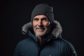 Portrait of a senior man in winter jacket and hat on black background