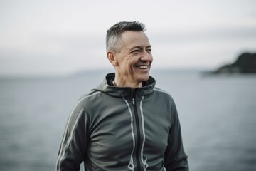 Portrait of a smiling middle aged man looking at camera while standing by the sea