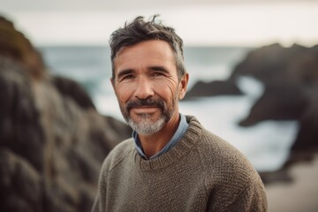Fototapeta premium Portrait of mature man looking at camera on the beach at sunset