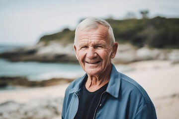 Fototapeta na wymiar Portrait of smiling senior man standing on the beach and looking at camera