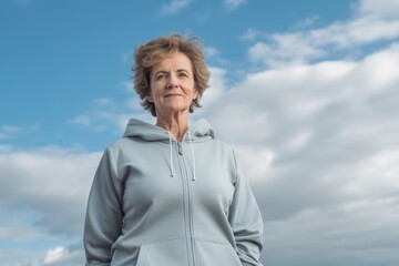 Lifestyle portrait photography of a pleased woman in her 50s wearing a comfortable tracksuit against a sky and clouds background. Generative AI