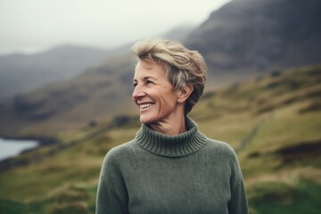 Naklejka premium Portrait of a happy senior woman standing in the middle of a mountain