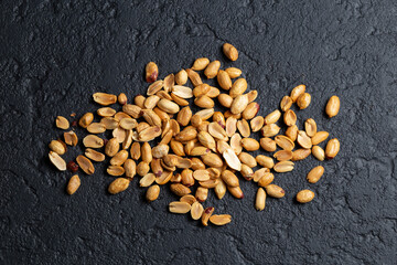 Pile of roasted peanuts on black background, space for text