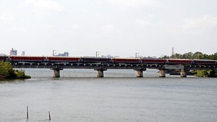 indian railway train moving very quickly on a bridge over the river in kerala