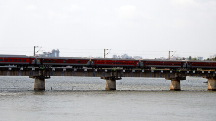 indian railway train moving very quickly on a bridge over the river in kerala