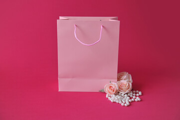 Conceito de presente de dia das mães. uma bolsa da moda e rosas  em um fundo rosa com espaço vazio para texto ou anúncio