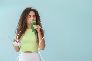 Young African-American woman with healthy food on light blue background. Diet concept