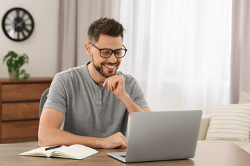 Man studying on laptop at home. Online translation course - obrazy, fototapety, plakaty