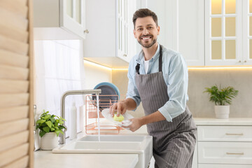 Man washing plate above sink in kitchen