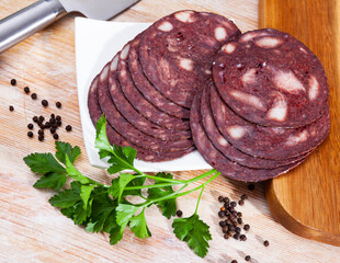 European cuisine blood pudding served with parley on white plate on wooden table