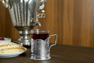 Vintage samovar, cup of hot drink and pancakes served on wooden table, space for text. Traditional Russian tea ceremony