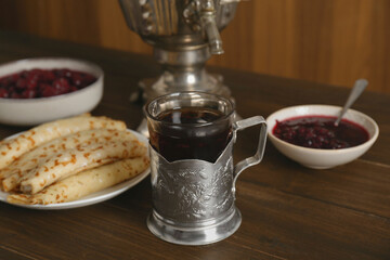 Vintage samovar, cup of hot drink and snacks served on wooden table. Traditional Russian tea ceremony