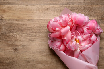 Beautiful bouquet of pink peonies on wooden table, top view. Space for text