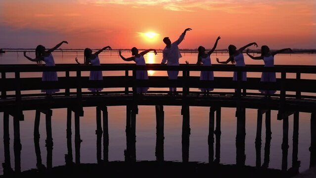 Graceful dancers do ballet moves standing on old bridge