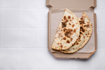 Tasty pizza calzones on white tiled table, top view. Space for text