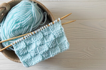 Soft turquoise yarn, knitting and needles on white wooden table, top view. Space for text