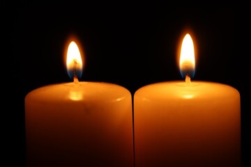 Burning wax candles on black background, closeup