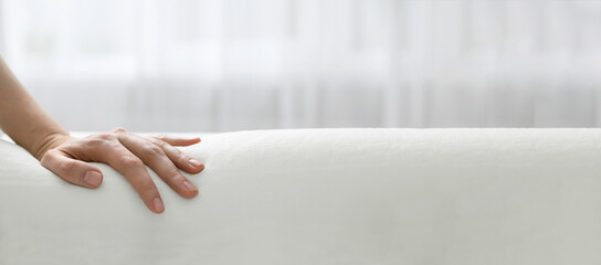 Woman touching memory foam pillow indoors, closeup. Banner design with space for text