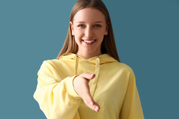 Teenage girl reaching out for handshake on blue background, closeup
