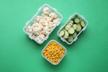Plastic containers with different fresh products on green background, flat lay