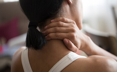The concept of sports injuries. Sports woman feels pain in her neck on a blurred background. Pain after home workout
