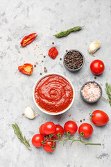 Composition with bowl of tomato sauce and ingredients on grey table