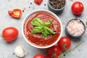 Bowl of tomato sauce and ingredients on grey table, closeup