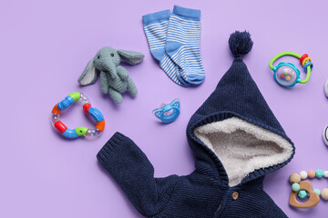Composition with baby clothes, toys and accessories on lilac background