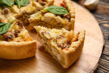 Pieces of mushroom pie with spinach leaves and champignons on brown wooden table